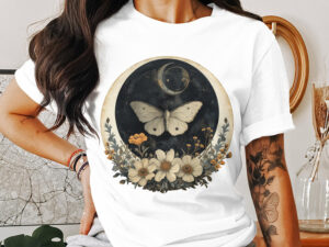 Sublimation design featuring a white moth, crescent moons, and vintage wildflowers in a circular celestial frame on a white t-shirt