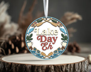 Lake Day Eh round PNG sublimation design with paddles, pine branches, fish, lantern, lake waves and cottage lettering